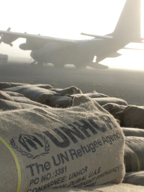 Humanitaerer Lufttransport mit Hilfsguetern vor einem Frachtflugzeug